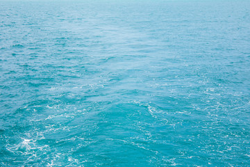 Sea wave water or surface of blue sea or ocean water behind back of transport ship or boat with sunlight at day time.