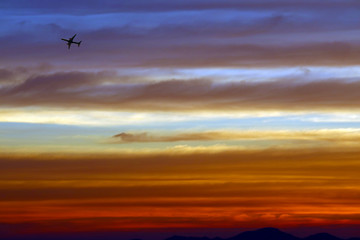 Fototapeta na wymiar airplane flying over the rainbow and blue sky red orange yellow cloud in sunset