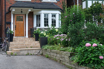 Fototapeta na wymiar front yard of older brick detached house with hydrangea flowers in bloom