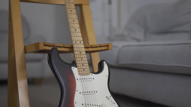 Slow motion of electric guitar leaning on a chair, during a music class.