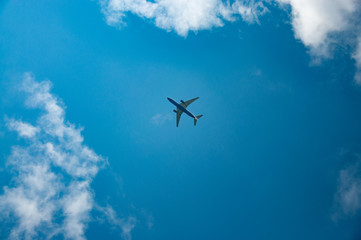 Fototapeta na wymiar Passenger plane flies in blue sky with white clouds around