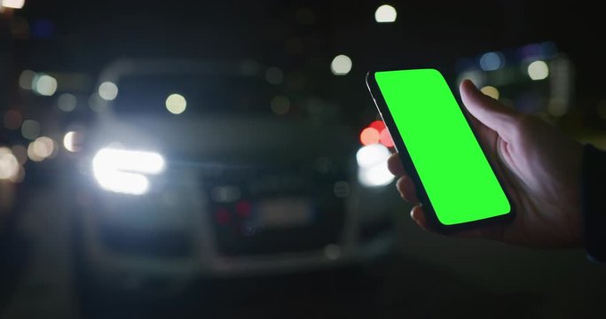 Close up of a businessman is using a smartphone as remote control of self pilot before a drive a car.