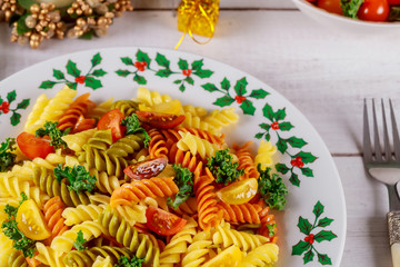 Italian colorful pasta rotini with cherry tomatoes on white wooden background.