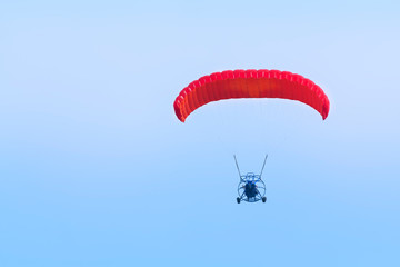 A paraglider with a motor on a sky background