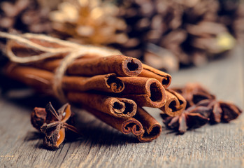 Christmas setting with bundle of cinnamon, anise stars and other christmas decorations on the rustic wooden background. Selective focus. Shallow depth of field.