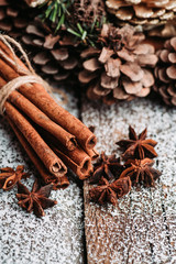 Christmas setting with bundle of cinnamon, anise stars and other christmas decorations on the rustic wooden background. Selective focus. Shallow depth of field.