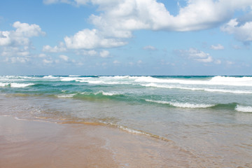 Sea foam on the sandy beach at Bat Yam, Israel. Waves on the blue stormy sea. Mediterranean coastline. Travelling picture. Turquoise water and sandy beach