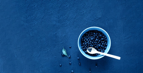 Bilberry in blue bowl. Concept of organic berries on dark background.