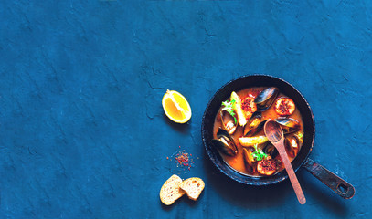 Mussels in red curry sauce on blue background.The concept of healthy and satisfying appetizer or light meal.Close-up
