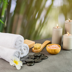 hot spa stones set for massage treatment, orchid flower, towels, candles and sea salt on green background with bamboo. Elegant and luxury spa. mock up, template. Health and beauty care concept