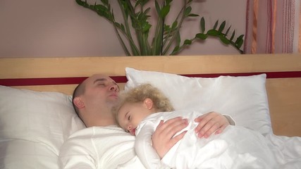 Cute little girl daughter lying on sleeping father man chest in bed
