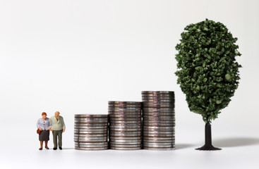 Old age miniature people and a miniature tree with a pile of coins.