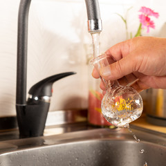 A man pours tap water into a glass flask.