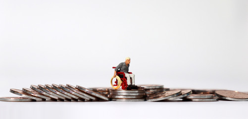 A miniature man in wheelchairs and coins. 