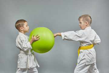 Serious little athlete is training to hit the green ball on a gray background