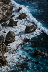 Aerial view to ocean waves with rocks. Blue water background. Bali, Indonesia.