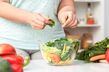 Body Care. Chubby girl standing near kitchen table making healthy salad close-up