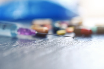 Medical syringe with a needle at the end of the drop. hypodermic syringe and colorful pills capsule on table background. drug medical healthcare surgery concept. Selective focus