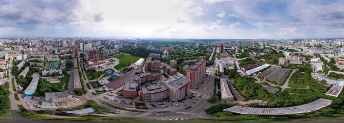 Aerial view of the city with traffic, streets and buildings with green trees and rails under the blue sky with clouds at summer day in Novosibirsk. Panoramic 360 degrees of the panet.