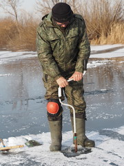 Naklejka premium elderly fisherman winter fishing on a river or lake