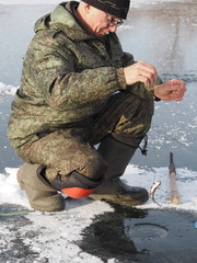 Naklejka premium elderly fisherman winter fishing on a river or lake