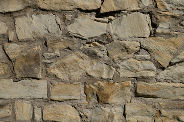 The texture is gray from irregularly shaped cobblestone. A yellowish wall connected by cement, a fence. Abstraction.