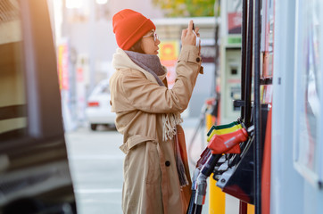 woman driver checking cost of gasoline, step flowing up and down of cost of gasoline in market...