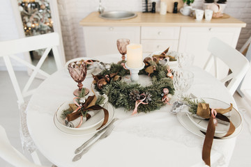Festive table setting among winter decorations and white candles. Top view, flat lay. The concept of a Christmas or Thanksgiving family dinner.