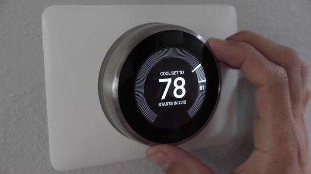 Man Adjusting Smart Thermostat Gadget At Home