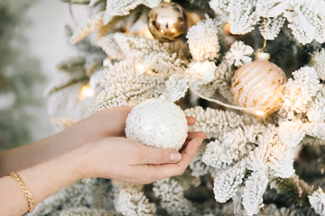 The girl's hands decorate the Christmas tree for the holiday, dress up with balls and garland