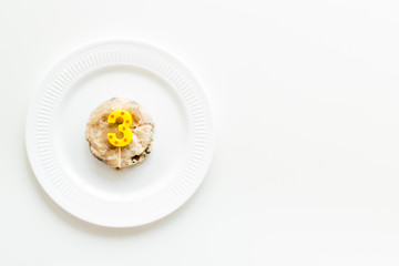 Cat's birthday concept. Pet feed with festive candle in shape of three on white background top-down copy space
