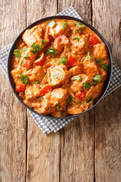 Spicy chicken mafe in peanut sauce, with tomatoes, pepper and coconut milk close-up in a plate. Vertical top view