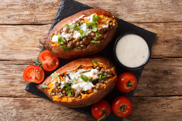 Organic whole baked sweet potato with lentils, garlic and parsley served with sour cream closeup on the table. Horizontal top view