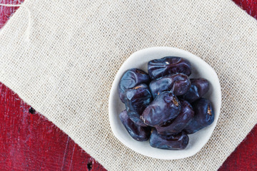Dried dates in ceramic plate over piece of sack