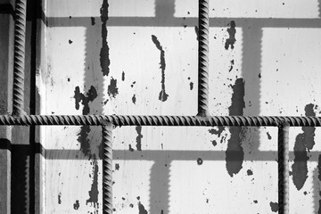 Fragment of an old painted window behind a rusty bars on a sunny day. Monochrome abstract background