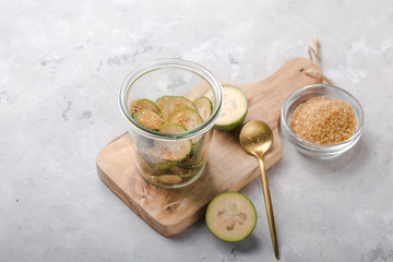 Ground green feijoa with sugar on a wooden cutting Board in a glass jar. Gray background. Top view. Healthy eating ingredients concept