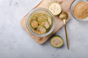 Ground green feijoa with sugar on a wooden cutting Board in a glass jar. Gray background. Top view. Healthy eating ingredients concept