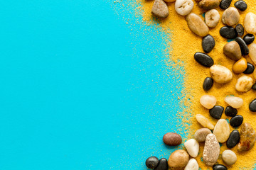 Resort or vacation concept. Sea stones and sand on blue background top-down frame copy space