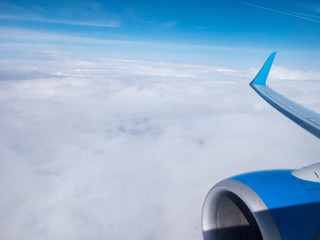 Clouds,clear bright blue sky, engine and wing of plane. Aerial view from plane illuminator