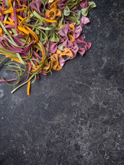 Homemade pasta, farfalle bow-tie, fettuccine or tagliatelle colorful pasta on grey background with flour, Colorful butterfly pasta. Italy ingredients for lunch.