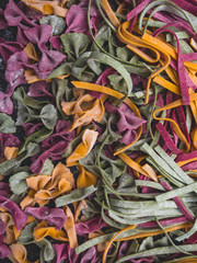 Homemade pasta, farfalle bow-tie, fettuccine or tagliatelle colorful pasta on grey background with flour, Colorful butterfly pasta. Italy ingredients for lunch.