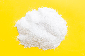 Washing powder scattered on yellow background top view