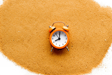 Waste of time concept. Clock on sand on white background top-down