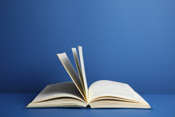 Open old hardcover book on blue background. Space for text