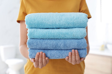 Woman holding fresh towels in bathroom, closeup
