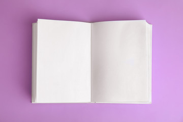 Open book with blank pages on violet background, top view