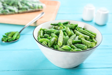Frozen cut green beans on light blue wooden table, closeup. Vegetable preservation
