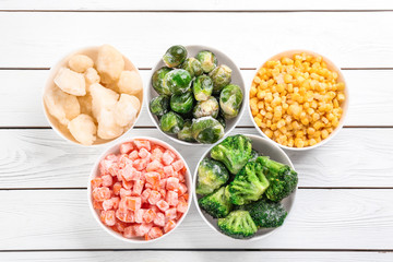 Different frozen vegetables on white wooden table, flat lay