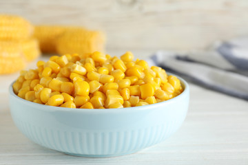 Delicious canned corn in bowl on white wooden table, closeup