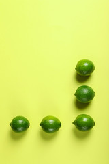 Flat lay composition with fresh juicy limes on yellow background, space for text
